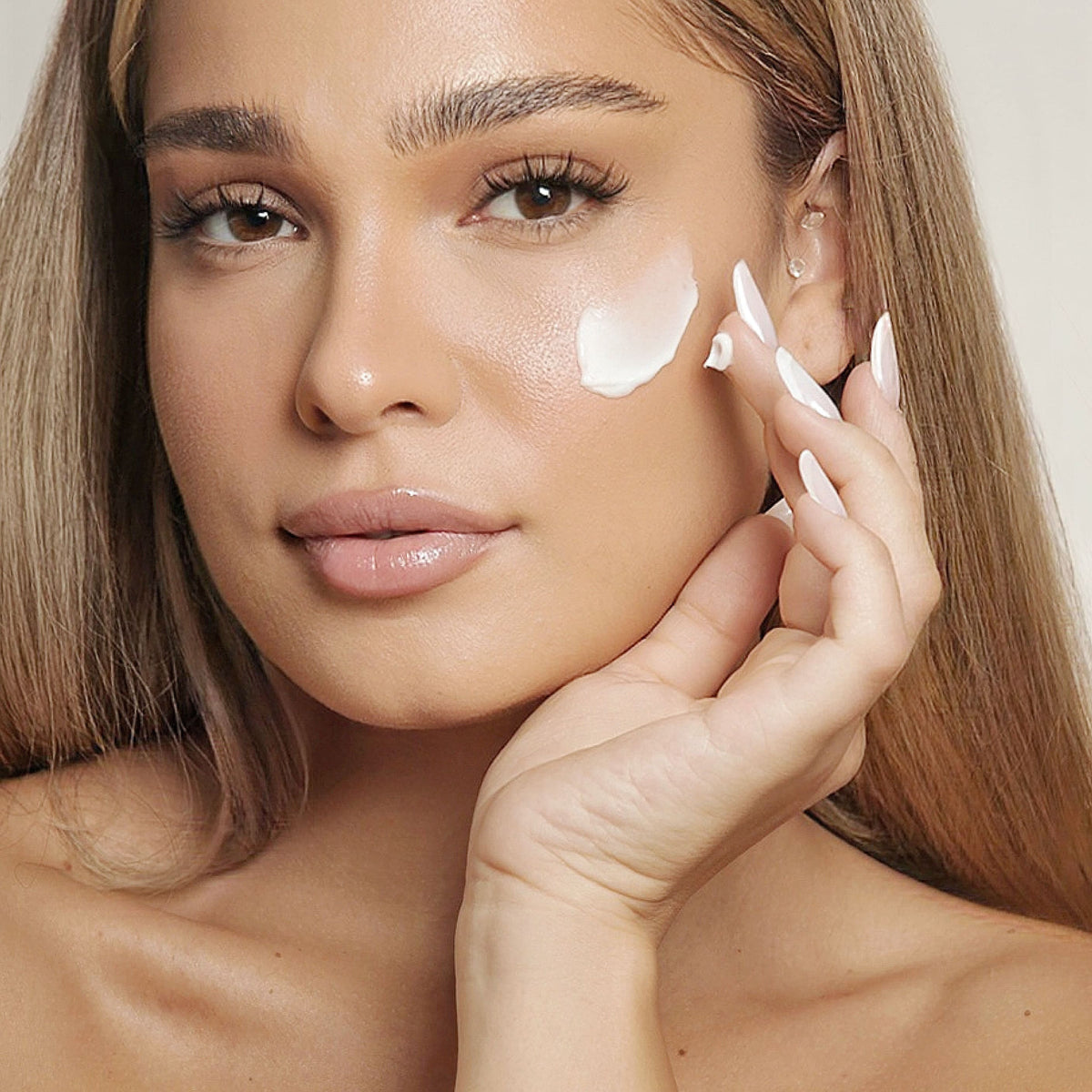 Prim-plan cu cremă aplicată pe obraz și privire directă, pentru Crema Hidratanta Natural Beauty by Laura Baldini.