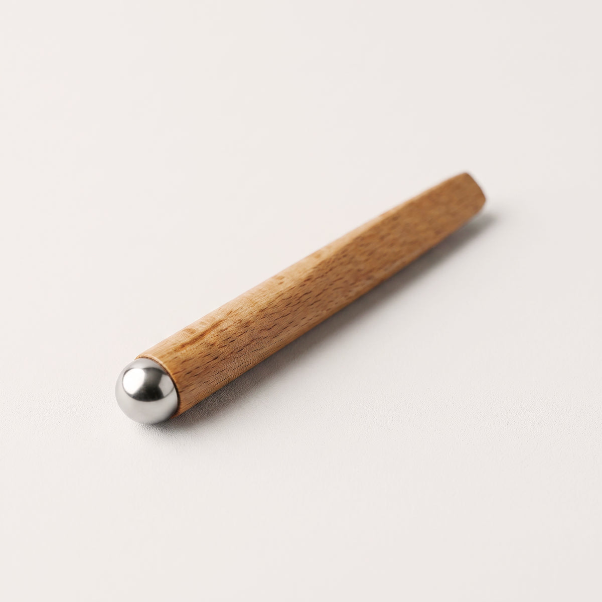 Rolă EYEZEN pentru masajul conturului ochilor, cu bilă din inox și mâner conic din lemn natural, culcată în diagonală
